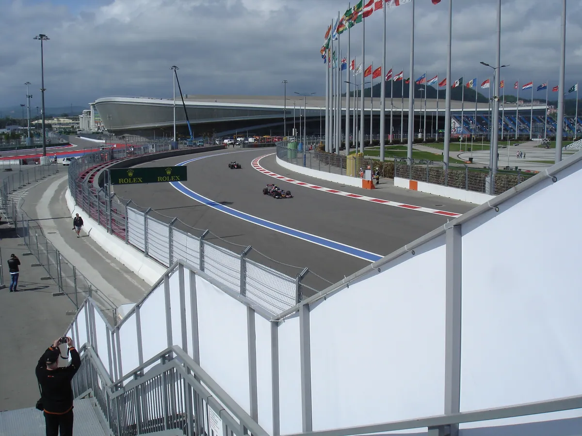 Un monoplaza de Toro Rosso rueda en el Gran Premio de Rusia 2016 en el Sochi Autodrom; detrás, otro coche y mástiles de banderas.