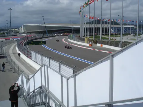 Un monoplaza de Toro Rosso rueda en el Gran Premio de Rusia 2016 en el Sochi Autodrom; detrás, otro coche y mástiles de banderas.