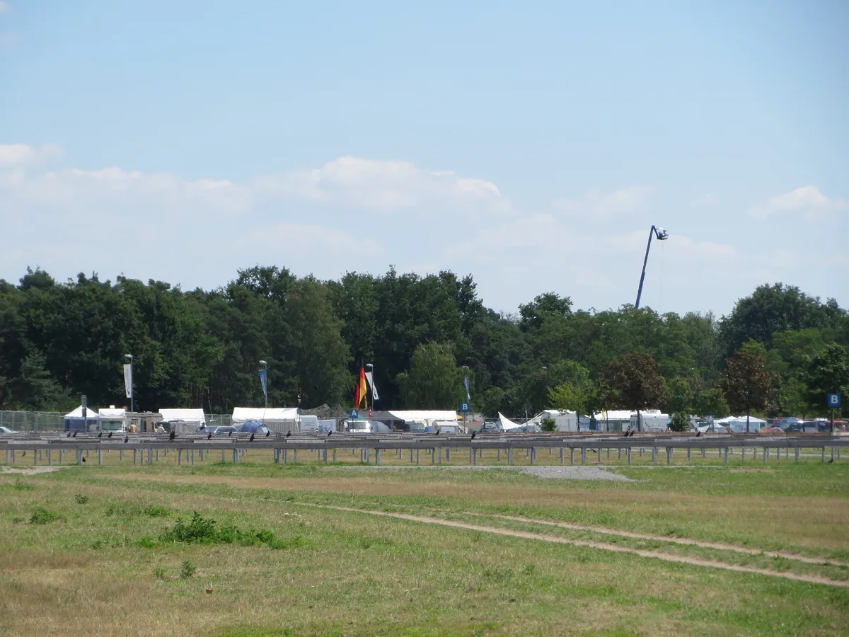 Zelte und Wohnwagen auf dem Campingplatz am Hockenheimring während des Rennwochenendes 2014, davor eine Wiese, dahinter Wald