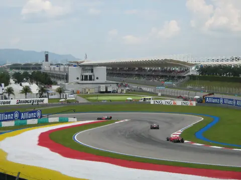 Drei Formel-1-Autos fahren im Qualifying zum GP Malaysia 2007 durch eine Kurve des Sepang International Circuit, dahinter die Haupttribüne